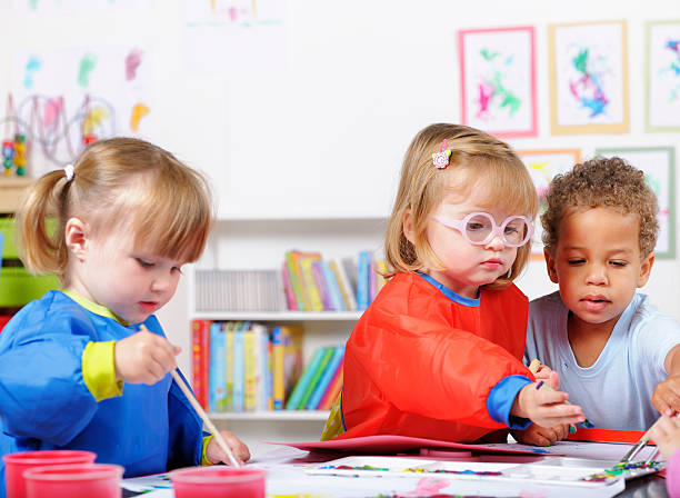 Group Of Toddlers Painting In A Nursery Setting