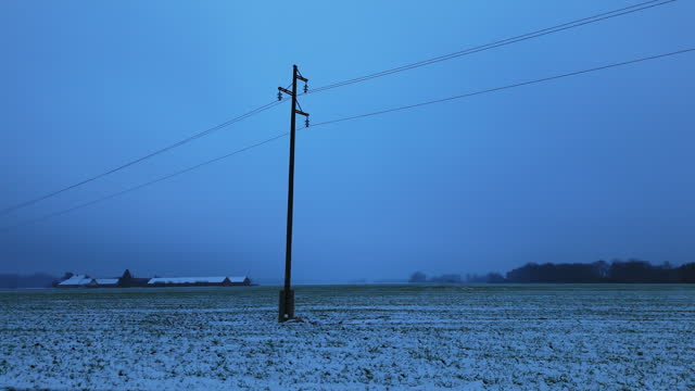 Drone Shot of Pylon Lines on Snow Covered Fields Under Sky During Blue Hour