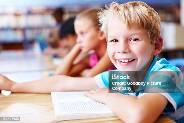 Linda Little Boy Sonriente Con Amigos En La Biblioteca Foto de stock y más banco de imágenes de Aprender