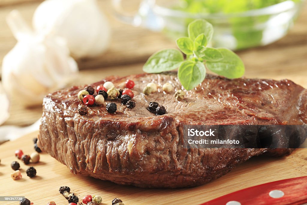 Roasted steak on a cutting board Roasted steak and pepper on a cutting board Basil Stock Photo