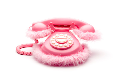 Isolated on white photograph of a pink retro telephone with feathers.