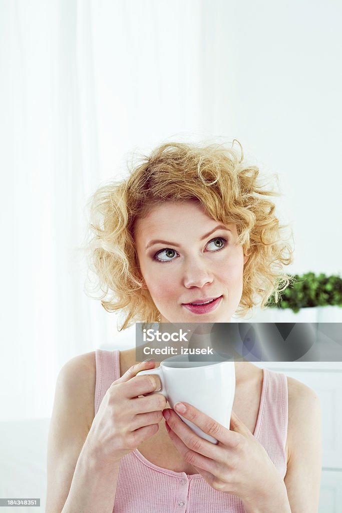 Morning caffee Pretty young adult woman wearing pink sleeveless top holding cup of coffee in the morning, looking up. 20-24 Years Stock Photo