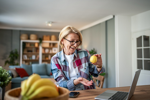 A mature woman enjoys a morning and a non-working day in her modern apartment, eating an apple