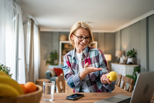 A mature woman enjoys a morning and a non-working day in her modern apartment, eating an apple