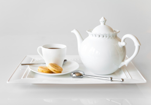 A tray with a teacup, teapot and cookies.
