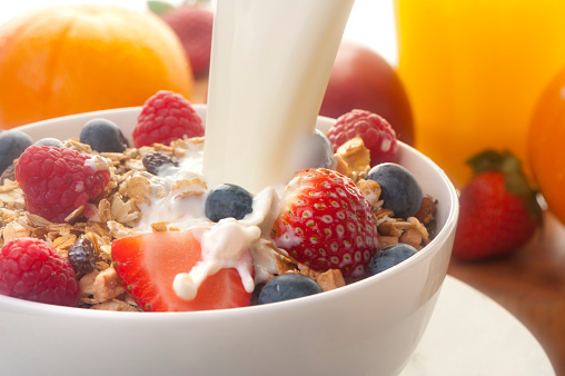 Healthy muesli breakfast with milk being poured over it