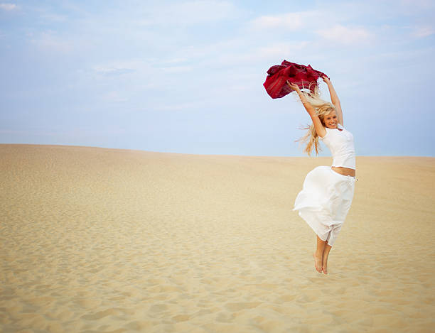 Young cheerful man in desert jumping high up in the air. 