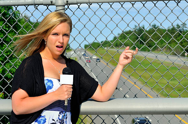 Female Reporter on Highway Overpass "Young blonde female reporting on traffic from a highway overpass. Highway is Rte. 101, shot in Candia, NH." mike cherim stock pictures, royalty-free photos & images