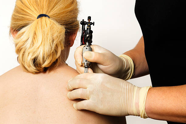 Woman getting her first tattoo young female getting her first tattoo. back shoulder tattoos for women pictures stock pictures, royalty-free photos & images