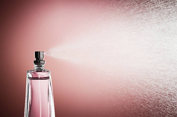 frasco de vidrio de perfume pulverización niebla contra fondo rosa - perfume sprayer fotografías e imágenes de stock