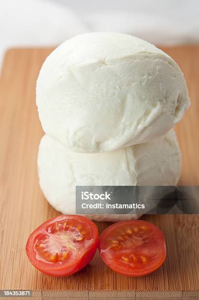 Photo libre de droit de Mozzarella Deux Balles Sur Une Planche À Découper Avec Des Tomates banque d'images et plus d'images libres de droit de Aliment cru