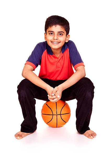 istock Isolated Relaxed Indian Boy Sitting on Basket Ball Full Length 184354080