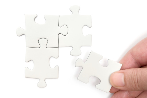 Person putting a blank puzzle piece into place. Isolated on a white background.