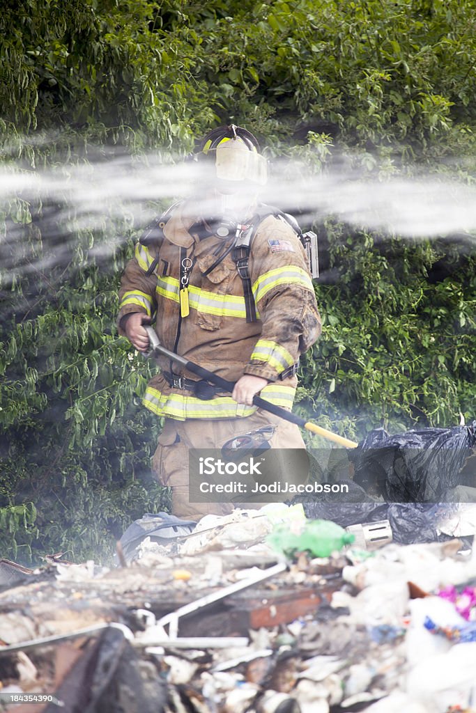 Fireman putting out trash fire Unrecognizable Fireman putting out a trash with water streaming in front of himChildren images Accidents and Disasters Stock Photo