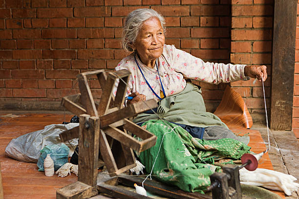 Nepali woman spinning the wool. Bhaktapur Old Nepali lady sitting on the Durbar Square and spinning the wool. patan durbar square stock pictures, royalty-free photos & images