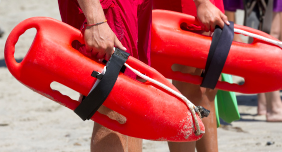 Two lifeguards holding their rescue buoys. .