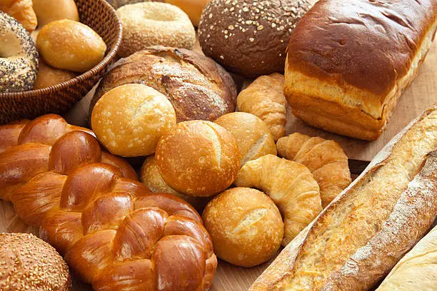 An assortment of bakery fresh breads.  Brioche, baguette, sourdough, rolls, bagels, challah, croissant and boule.  Shallow dof