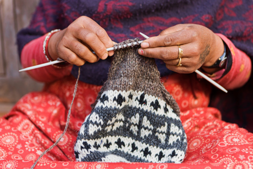Nepali woman kniting a wool hat in front of the house. Bhaktapur in Kathmandu valley. Nepal.