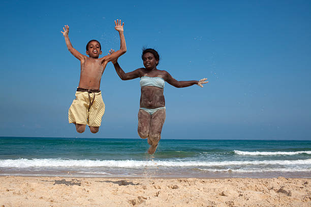 Group of silhouettes of happy young friends are having fun and jumps together at sunset sea beach