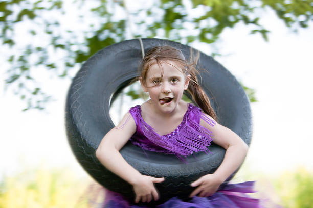 bambina oscillante su altalena con pneumatico - freedom tire swing tire swing foto e immagini stock
