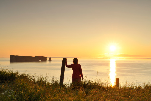 Woman admiring the beautiful sunrise on Perce Rock.