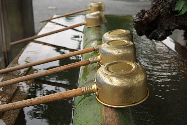 Metal cups attached to a wooden handle are used to clean one's hand with water from a trough before entering a temple or shrine in Japan.