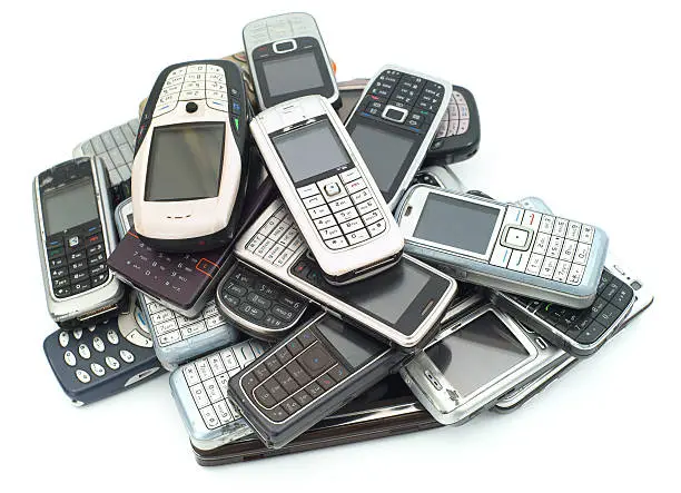 Old used cellphones pile isolated on white