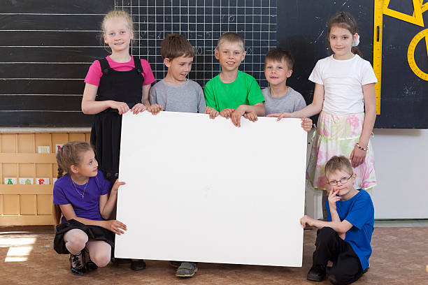 istock School kids holding blank informational sign 184358675
