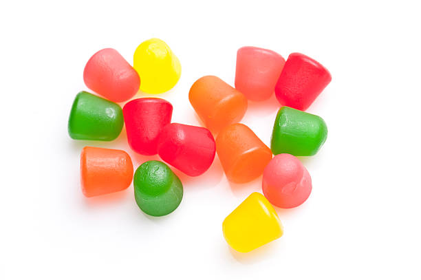 Gummy Candies colorful assorted gummy candies coming out of the bag on white background chewy stock pictures, royalty-free photos & images