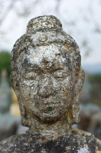 A portrait of an old stone statue of Buddha.