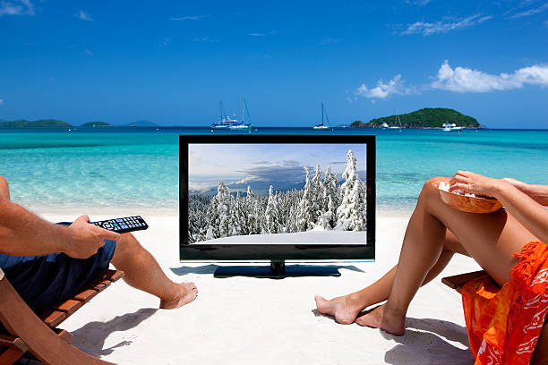 escenas de invierno de pareja mirando televisión en una playa tropical - women sarong beach white fotografías e imágenes de stock