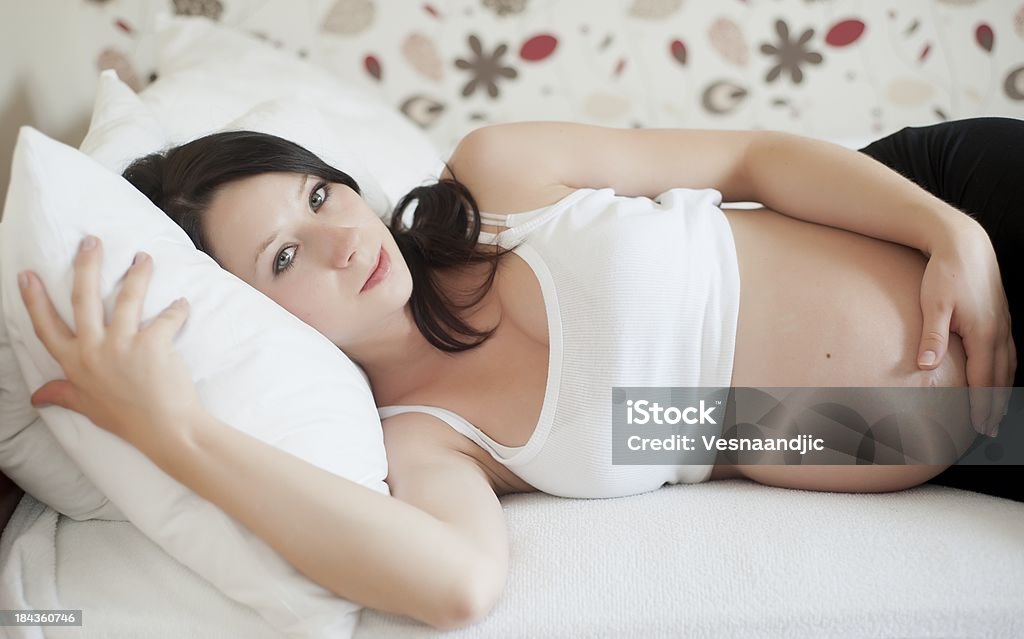 Pregnant woman Beautifull young pregnant woman holding her belly and lying in bed 35-39 Years Stock Photo