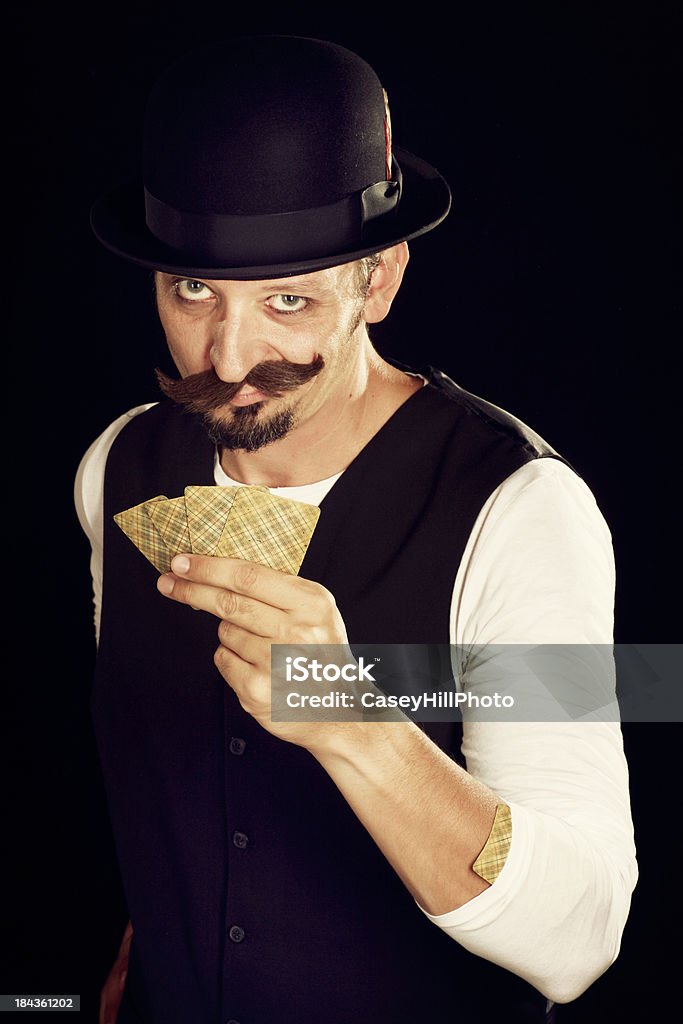 Card Shark "Vaudeville style magician in a bowler derby, mustache and vest holding cards. (Note: these are very old vintage playing cards.)" Vaudeville Stock Photo