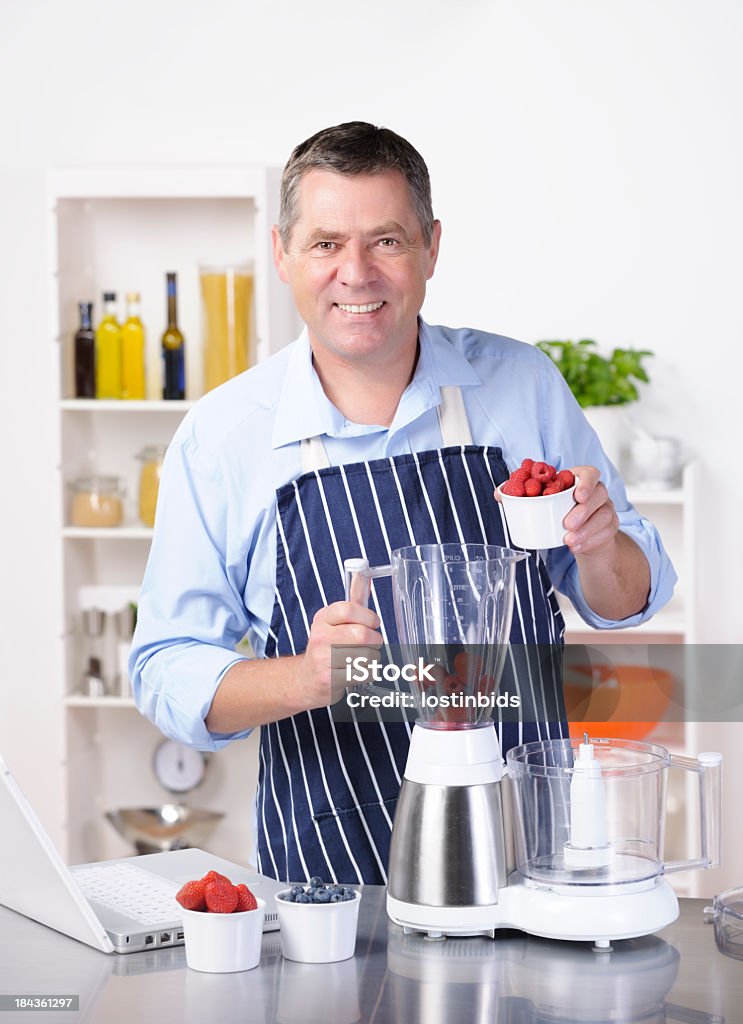 Homem Maduro servindo frutas no liquidificador durante Smoothie/sobremesa fazer - Foto de stock de 50 Anos royalty-free