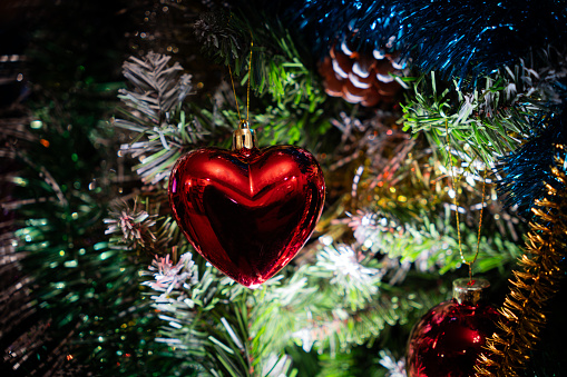 Christmas background with red heart shape hanging on fir sprigs