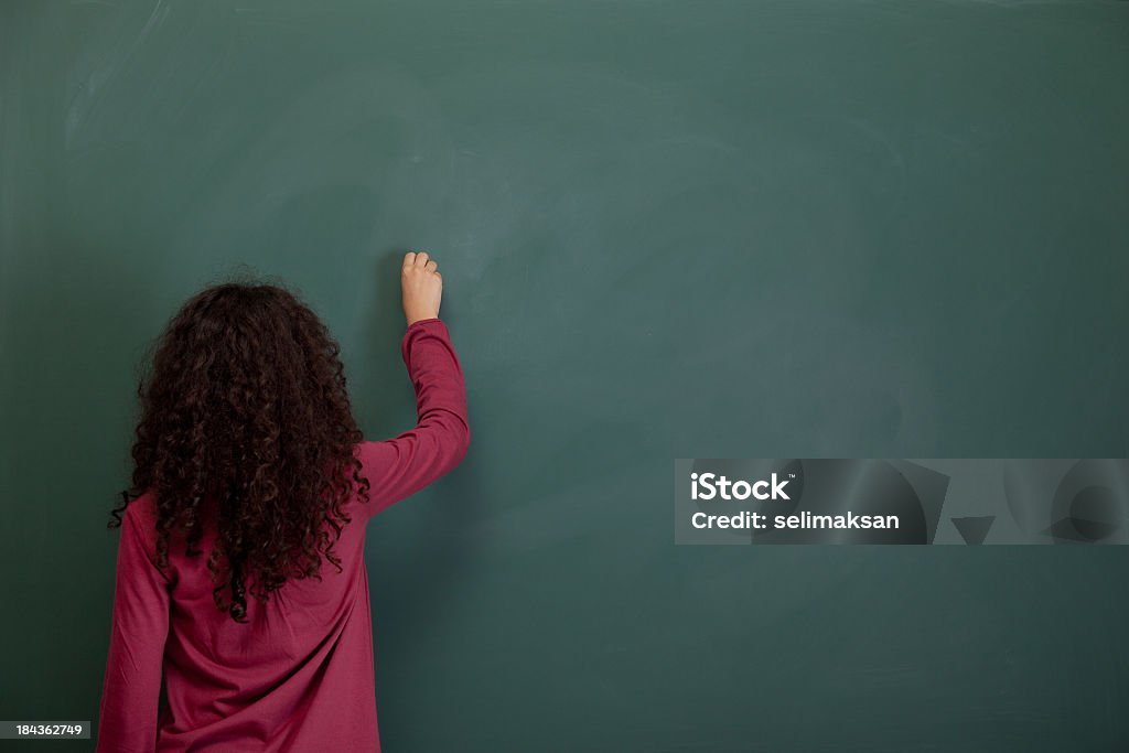 Vue arrière de petite fille écrit sur le tableau noir vide - Photo de Tableau libre de droits