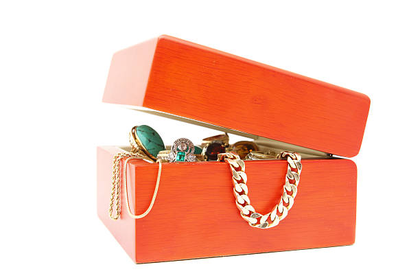 colorful jewelry and costume jewelry lie in a red open box stands on a yellow wooden table