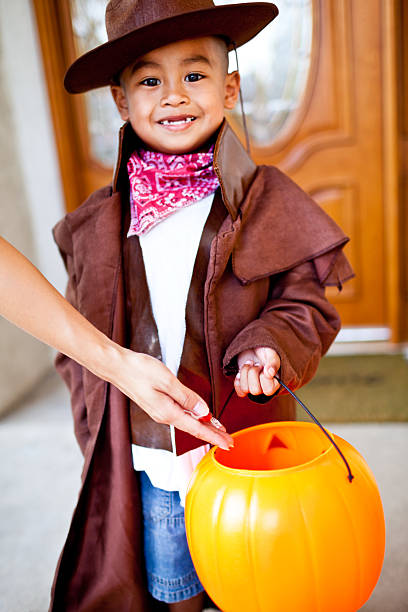 istock Little cowboy on halloween recieving candy 184363455
