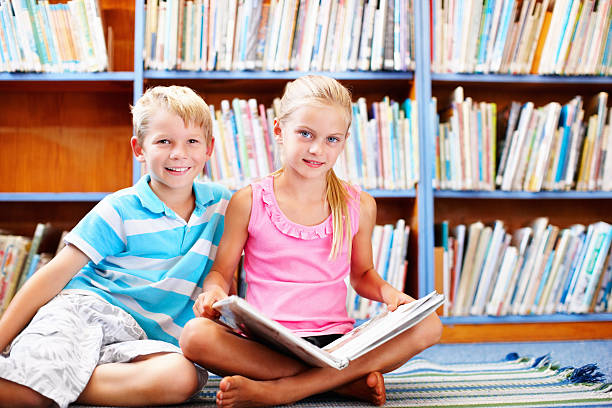 istock Cute, little kids sitting with a book in the library 184364085