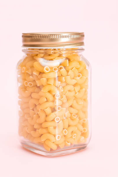 istock Uncooked Chifferi Rigati Pasta in Glass Jar on Pink Background 1843644795