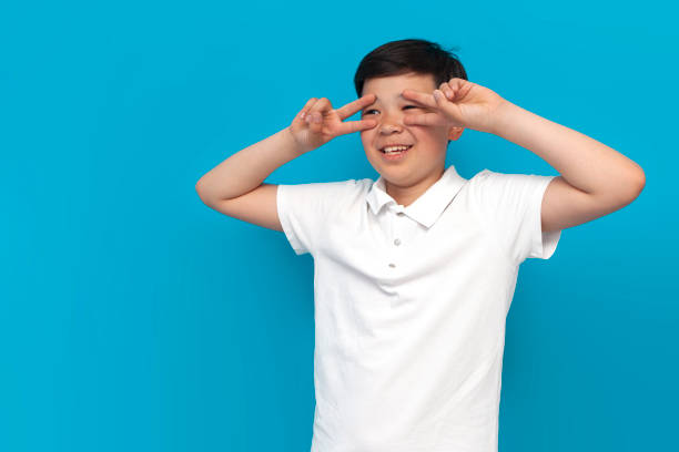 istock asian boy showing peace gesture on blue background, korean child posing over isolated background 1843645245