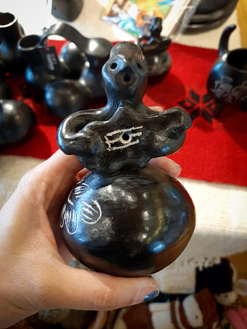Human hand holding black ceramic craft