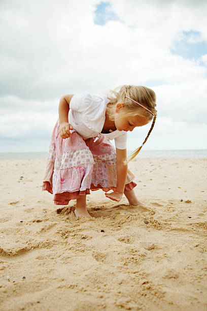 istock Little Girl Playing with Sand on the Beach 184364808