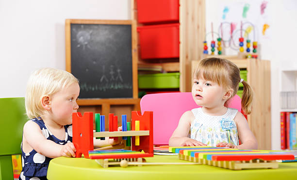 istock BlondeToddler And Peer Playing With  Multi-coloured Toy In A Nursery 184365831