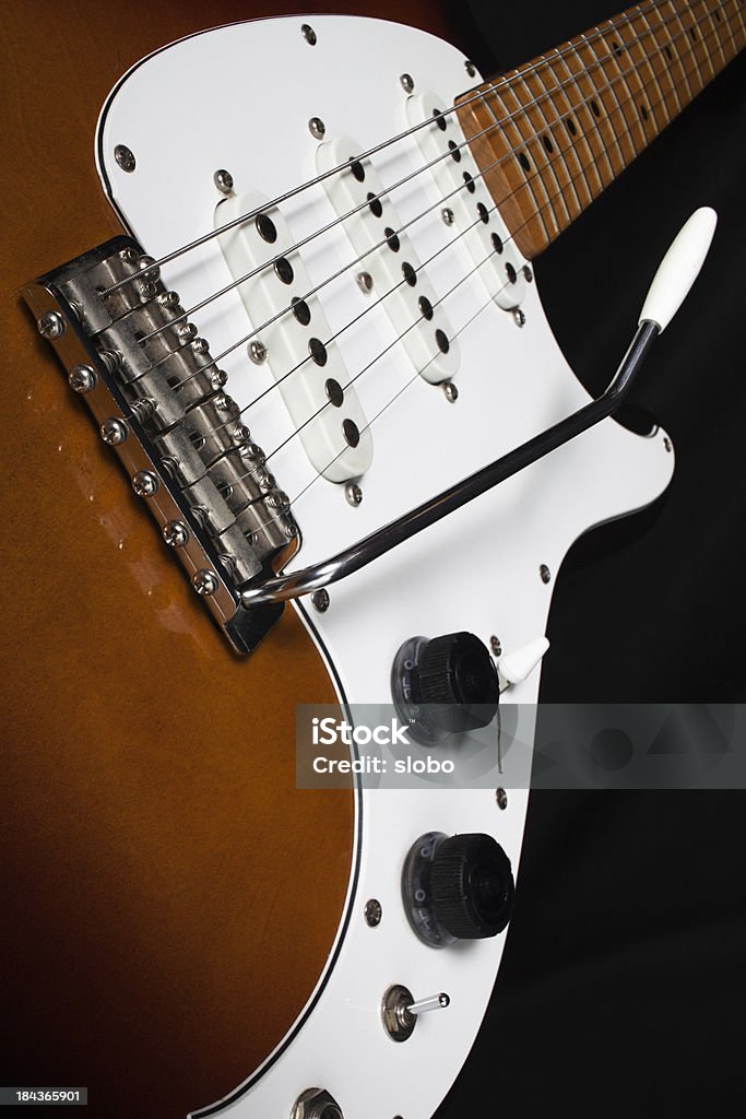 Vintage Electric Guitar with Tremolo Bar Vintage sunburst three single coil pickup guitar with tremolo bar against dark background. Arts Culture and Entertainment Stock Photo