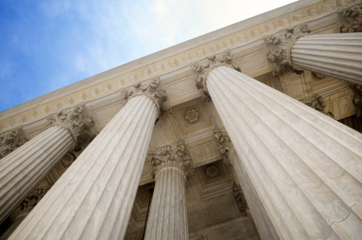 Grand classical stone columns soar up to decorative entablature at the Supreme Court building