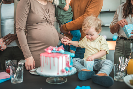 A mother and her little son are all smiles at a gender reveal party as they eagerly anticipate the arrival of a new family member.