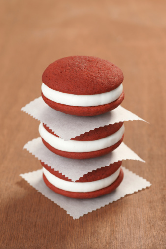 Three red velvet whoopie pies in a stack.