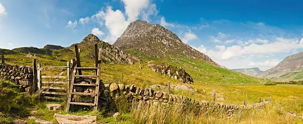 "Wooden stile over traditional dry stone wall on the trail head to Tryfan, the iconic rocky ridge climb in the heart of the Snowdonia National Park, Wales, UK. ProPhoto RGB profile for maximum color fidelity and gamut."