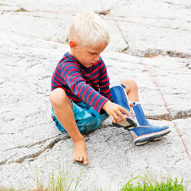 istock Wrong foot. Small blond boy putting on booths. 184371217
